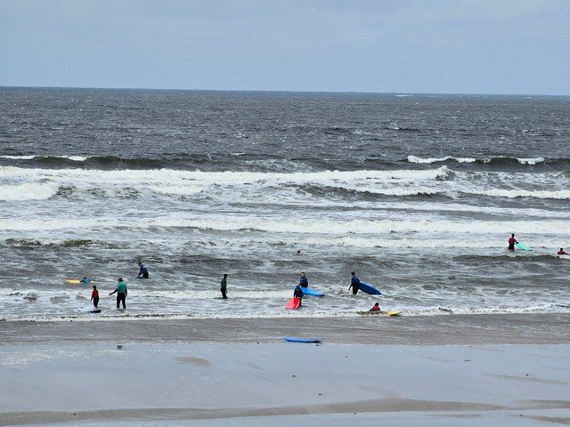 A beginner surfer class in the shallows as bigger waves break out the back